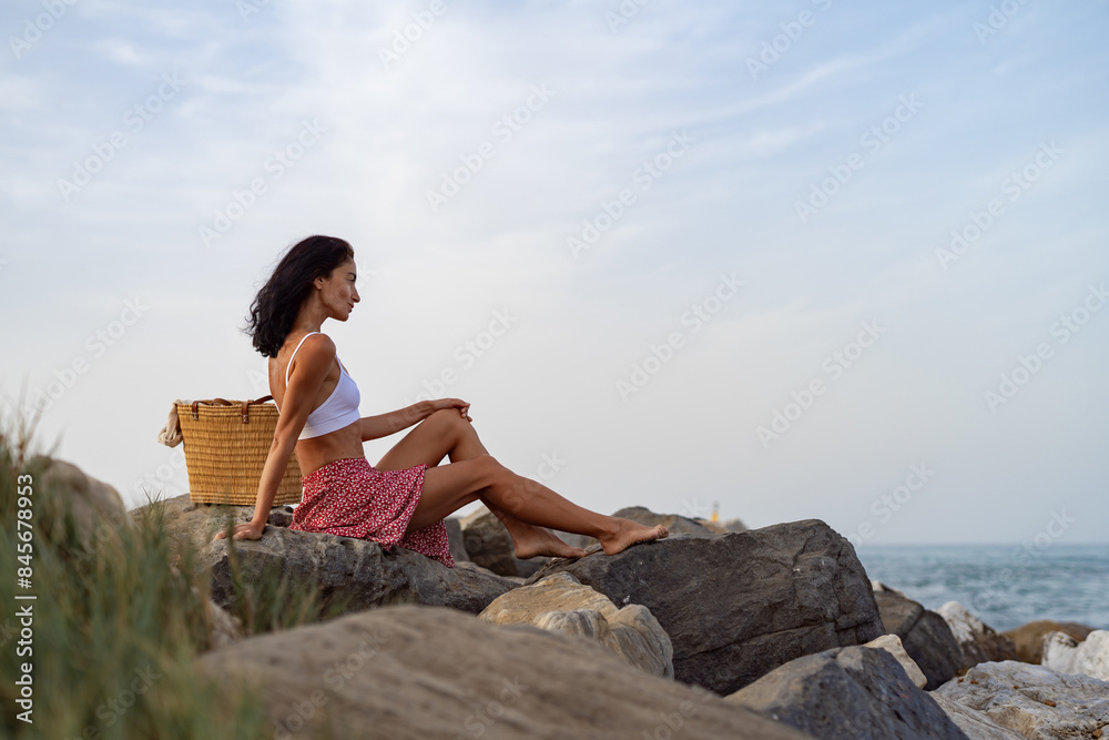 Woman Sitting on Rocks by the Sea Woman Sitting on Rocks by the Sea