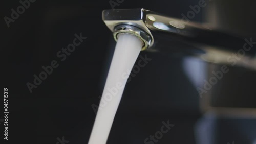 Water Coming Out Of The Faucet. Close up of tap while the water comes out. Chrome faucet. selective focus. save water concept.