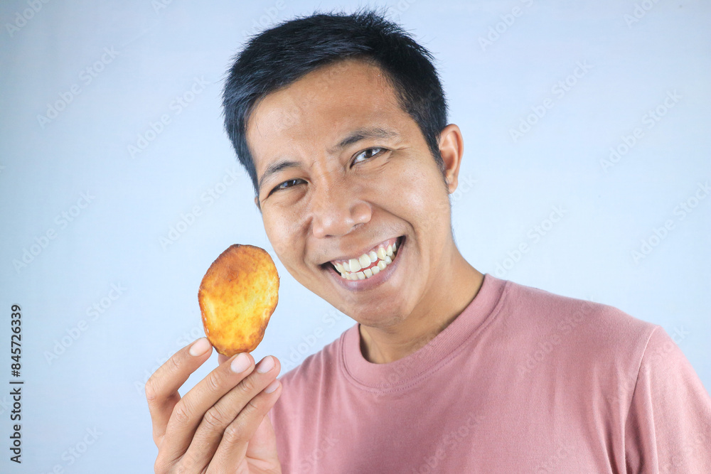 Smiling face expression of young asian man holding french fries, isolated on white background Smiling face expression of young asian man holding french fries, isolated on white background