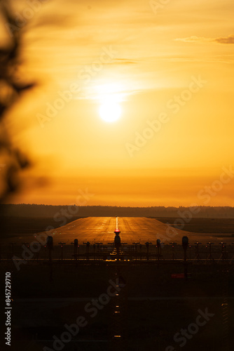 Helsinki, Finland - May 31st 2024: Sunrise, golden sky and warm light, early morning. Sun rising right above a runway airport in Helsinki-Vantaa International.