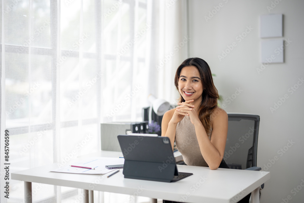 A woman is sitting at a desk with a laptop and a tablet A woman is sitting at a desk with a laptop and a tablet