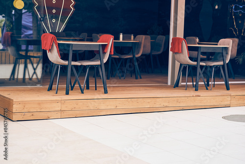 The outdoor terrace of the restaurant with an elegant design of tables and chairs on the floor covering, tiles. In black and red tones. With the ability to copy. High quality photo