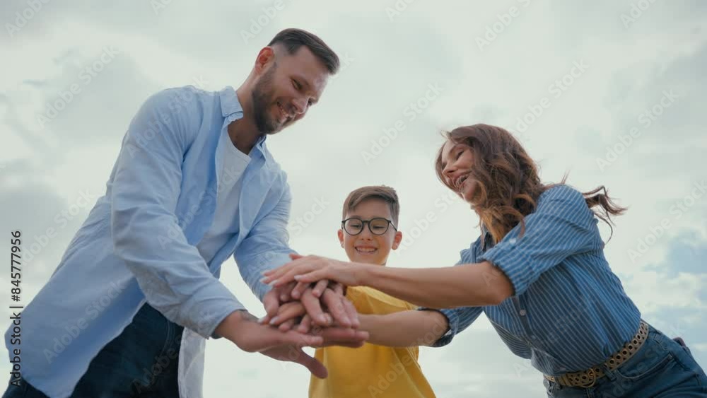 Caucasian happy family woman female mom male man dad putting stack hand little boy son child kid hands holding together raise arms air sky showing unity successful team gesture winner teamwork victory