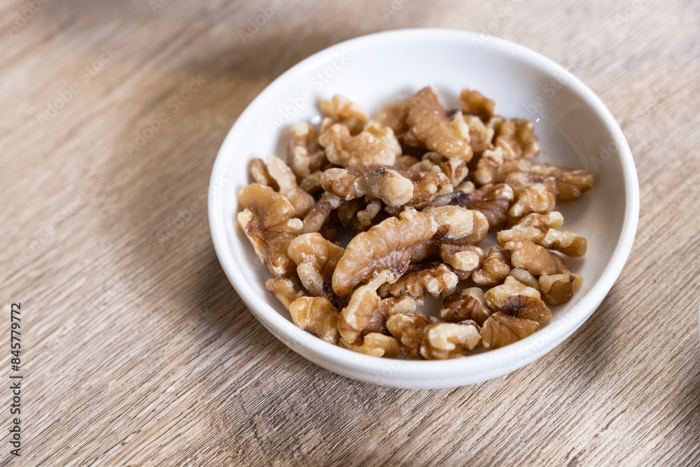 Walnuts in a container on the wooden floor Walnuts in a container on the wooden floor