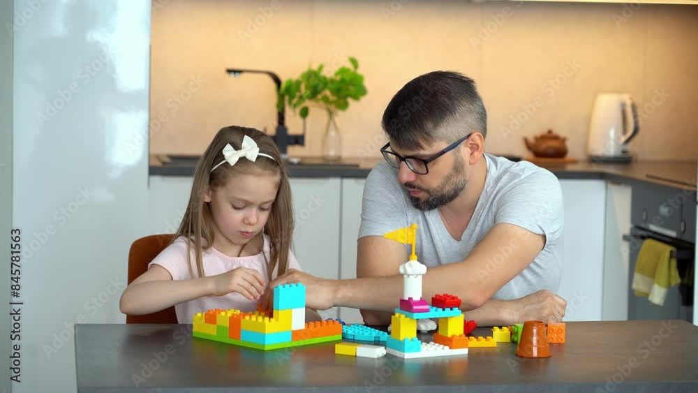 Father and daughter build plastic brick of construction set at home. Happy family play with construction kit. Building set. Leisure Father and daughter build plastic brick of construction set at home. Happy family play with construction kit. Building set. Leisure
