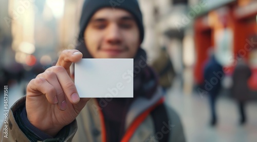 Close up of a man's hand holding a blank business card mockup, a white paper with space for text in front view.