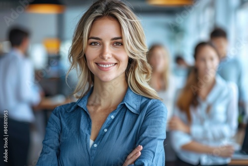 Smartly dressed businesswoman with a confident smile in front of her team in the office