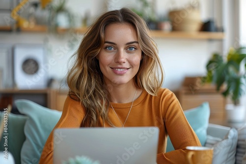 Confident woman holds a cup of coffee while working on her laptop, showcasing a relaxed work environment