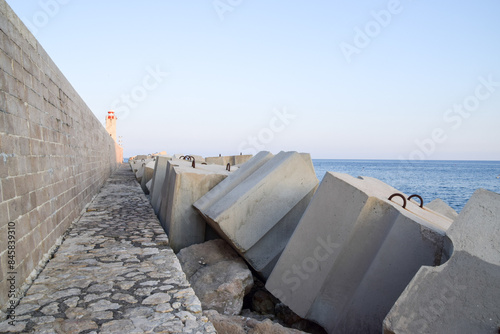 Large protective concrete blocks next to a seawall and lighthouse