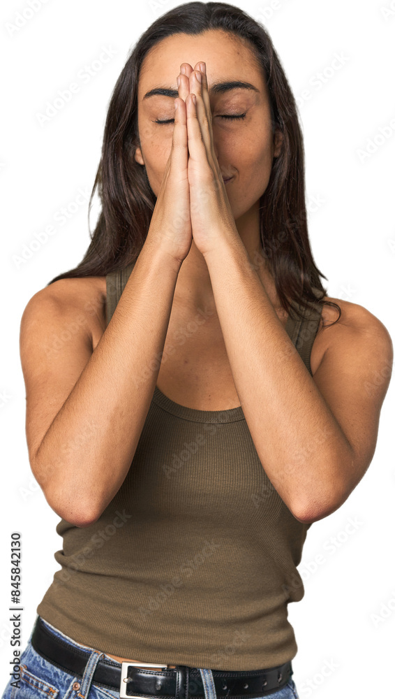 Fototapeta premium Hispanic young woman holding hands in pray near mouth, feels confident.