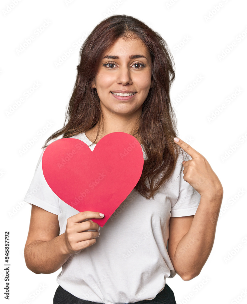 Middle Eastern woman holding paper heart smiling and pointing aside, showing something at blank space. Middle Eastern woman holding paper heart smiling and pointing aside, showing something at blank space.