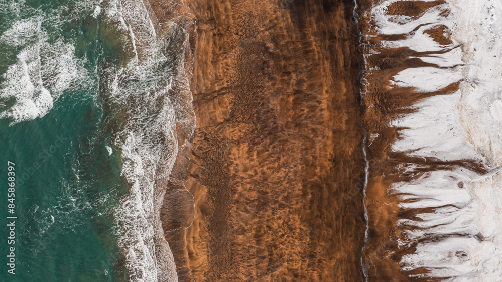 Drone view of splashing seawater against snow capped mountain