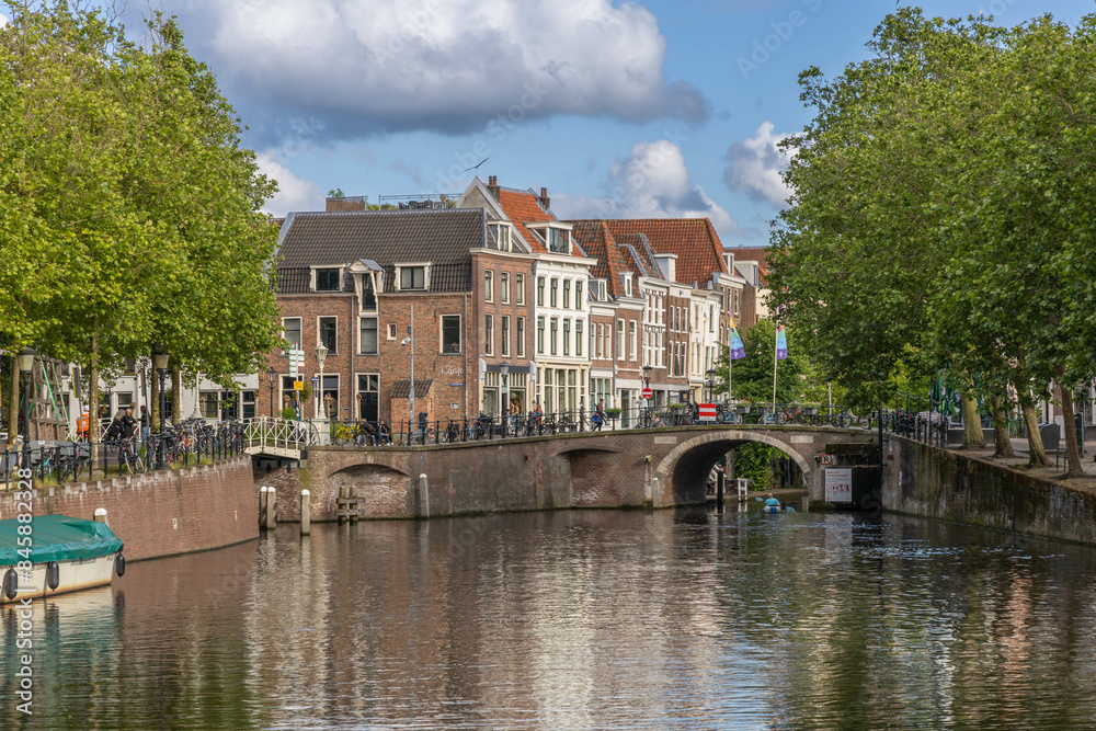 Naklejka premium River de Vecht Utrecht with green trees, old brick buildings and a arch bridge in the distance