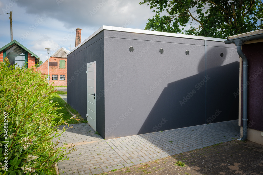 a newly built double garage with roller doors stands under a tree