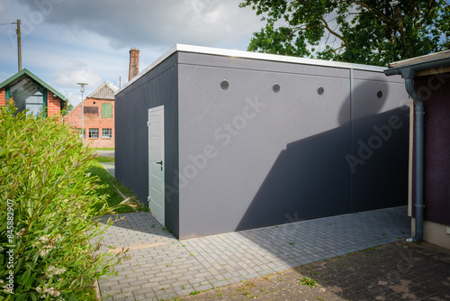 a newly built double garage with roller doors stands under a tree