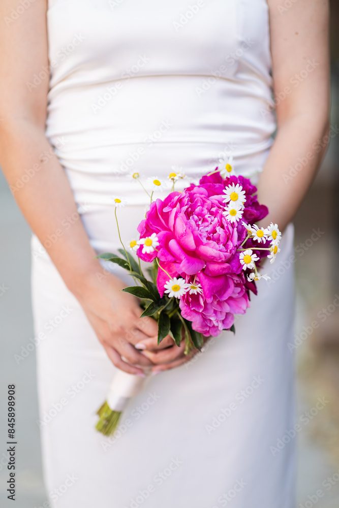 torso of bride holding pretty bouquet of peonies and daisies torso of bride holding pretty bouquet of peonies and daisies