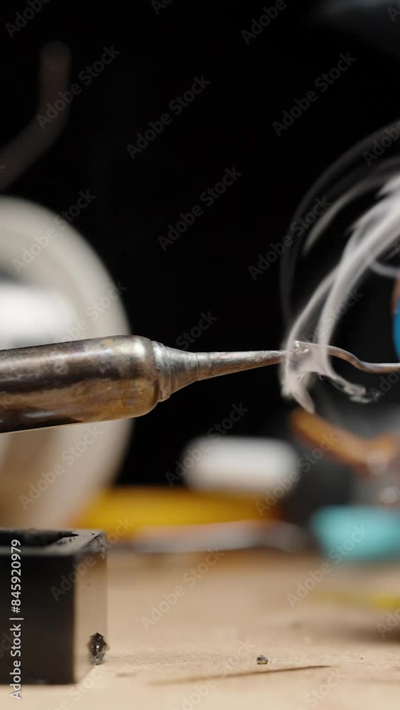 Vertical video. Man Applying Tin Solder from a Special Container to the Soldering Iron Tip, Melting and Emitting Lots of Smoke. Workshop Table. Vertical video. Man Applying Tin Solder from a Special Container to the Soldering Iron Tip, Melting and Emitting Lots of Smoke. Workshop Table.