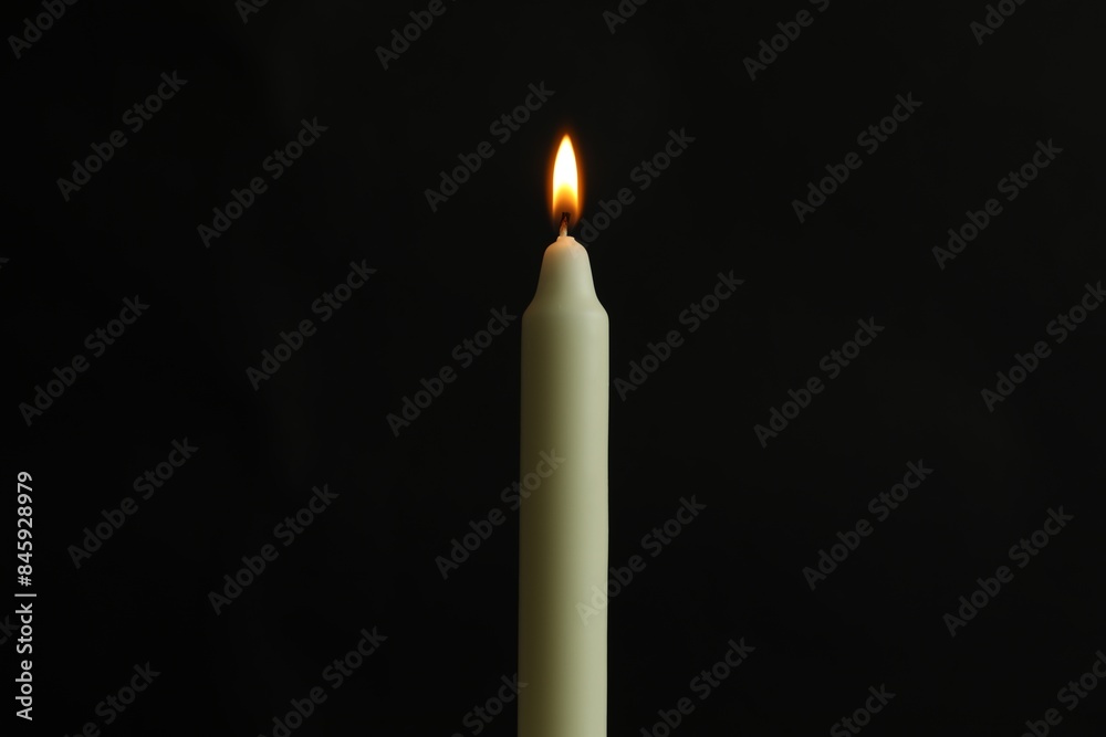 One burning church candle on black background One burning church candle on black background