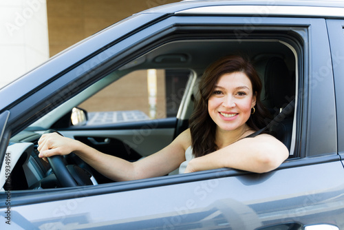 Smiling woman driving her car confidently, looking at the camera with a cheerful expression, embodying independence and mobility