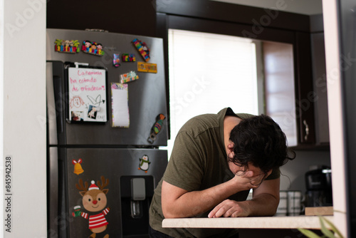 Young with lumbar pain in the kitchen using a lidocaine patch in the lower back
