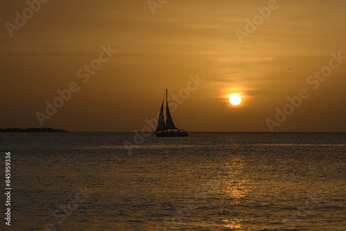 Valokuva Scenic view of sun setting in Caribbean sea with a sail boat silhouette on horizon