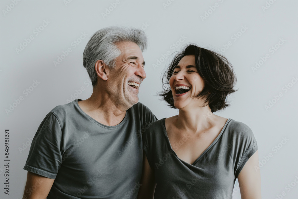 Elderly man and woman laughing together in gray shirts, happiness and joy concept Elderly man and woman laughing together in gray shirts, happiness and joy concept