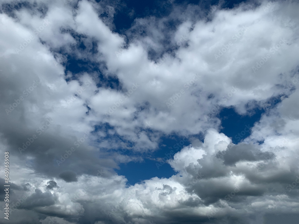 Fototapeta premium A view of the sky showing white and gray cumulus clouds against a blue sky on a bright, sunny day