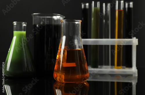 Laboratory glassware with different types of oil on black background