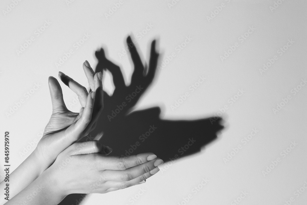 Obraz premium Shadow puppet. Woman making hand gesture like deer on light background, closeup with space for text. Black and white effect