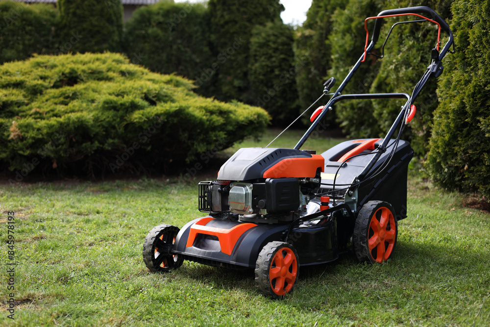 Modern lawn mower on green grass in garden Modern lawn mower on green grass in garden