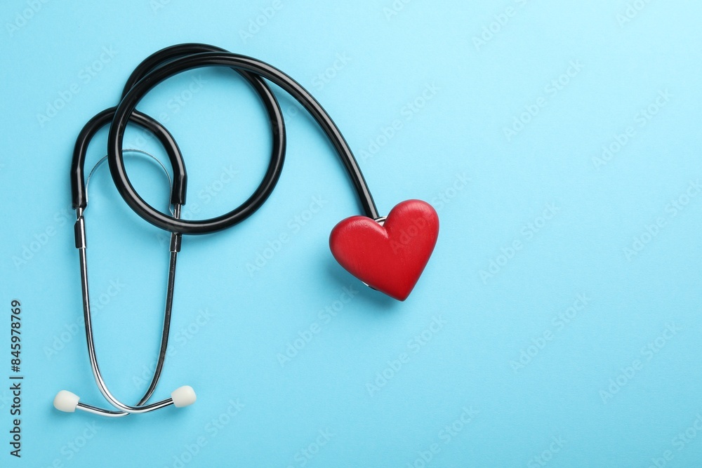 Stethoscope and red heart on light blue background, top view. Space for text Stethoscope and red heart on light blue background, top view. Space for text