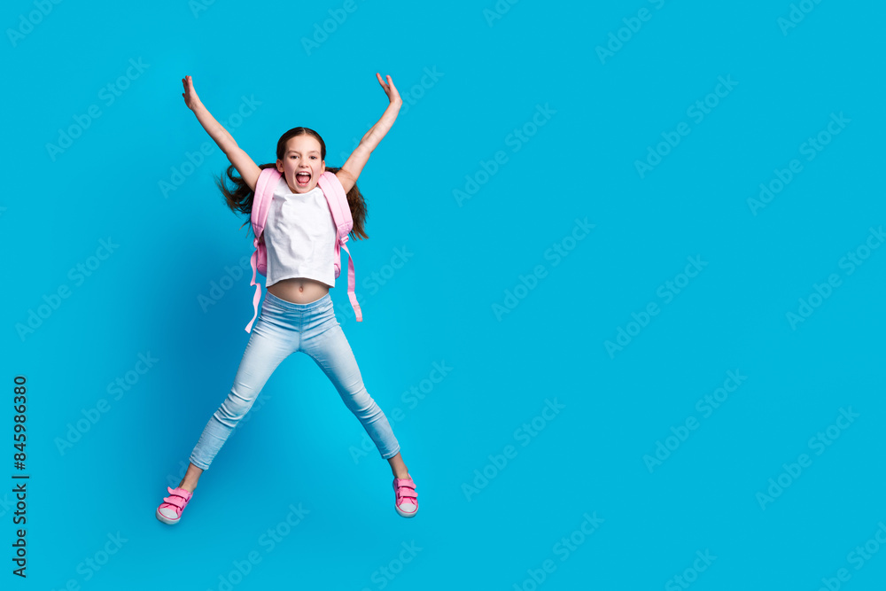 Photo of charming positive girl wear white t-shirt rucksack jumping high empty space isolated blue color background