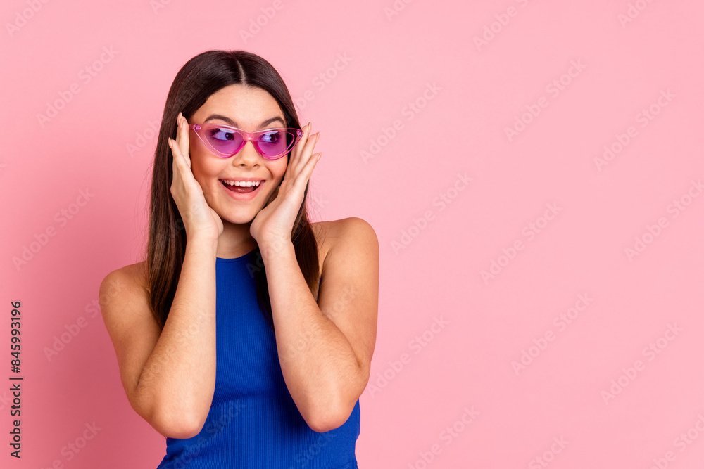 Photo of shiny excited lady dressed blue singlet dark eyewear looking empty space isolated pink color background Photo of shiny excited lady dressed blue singlet dark eyewear looking empty space isolated pink color background