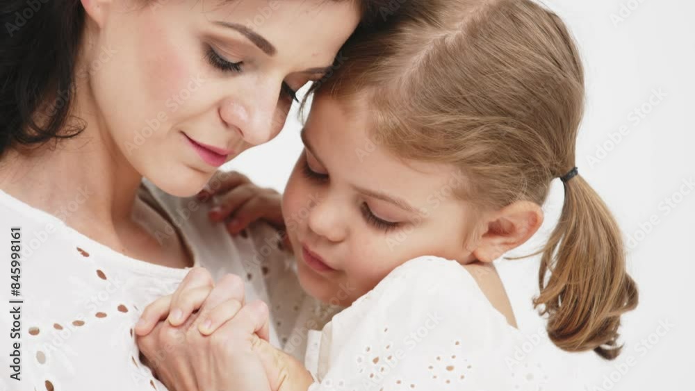 Family relationships between mother and daughter. Sensual mother with her little daughter on a light studio background. Tender moment, family support.