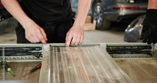 Arabian Male Technician Repairing An EV Car Battery Module In A Workshop. Automobile Engineer Working On An Electric Vehicle Battery Module Separately From The Vehicle. Auto Service