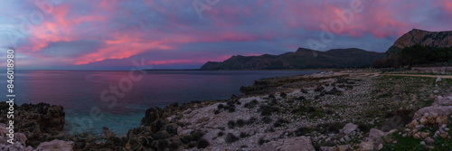 Panoramia of coast with turquoise water at Nature Park Monte Cofano during evening twilight with red illuminated sky, San Vito Lo Capo, Sicily, Italy photo