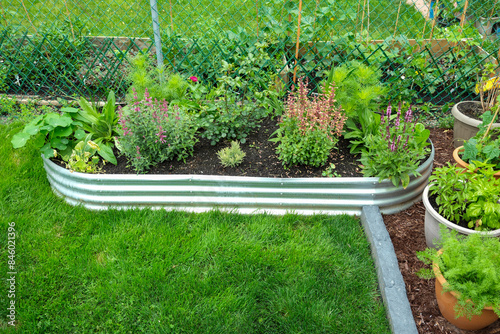 portable garden with galvanized metal raised garden beds. a mulched area holds many vegetable plants in containers