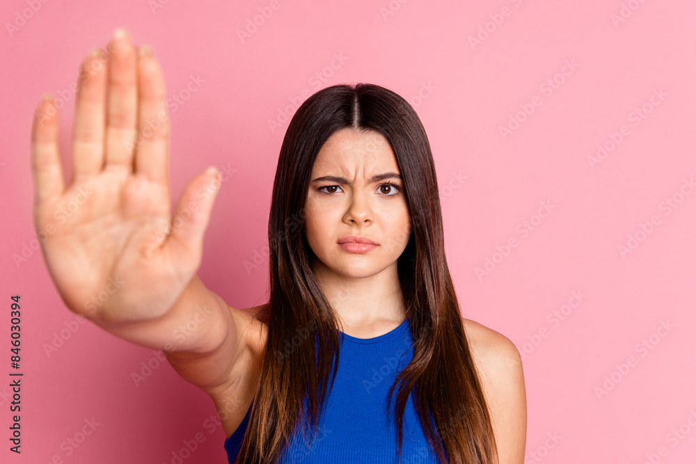 Photo of serious confident lady dressed blue singlet showing arm stop empty space isolated pink color background Photo of serious confident lady dressed blue singlet showing arm stop empty space isolated pink color background