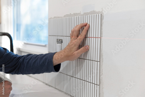 Installing ceramic wall tile. Tiling kitchen backsplash