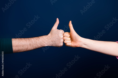 Photo of two people making thumb up sign bumping isolated dark color background