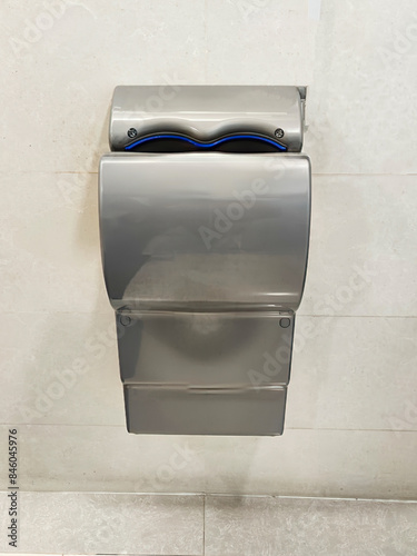A modern hand blower in a public toilet, sleek and silver for drying hands. Efficient and hygienic