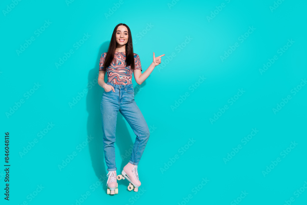 Full length photo of girlish pretty lady dressed retro top enjoy roller skating showing finger empty space isolated blue color background Full length photo of girlish pretty lady dressed retro top enjoy roller skating showing finger empty space isolated blue color background
