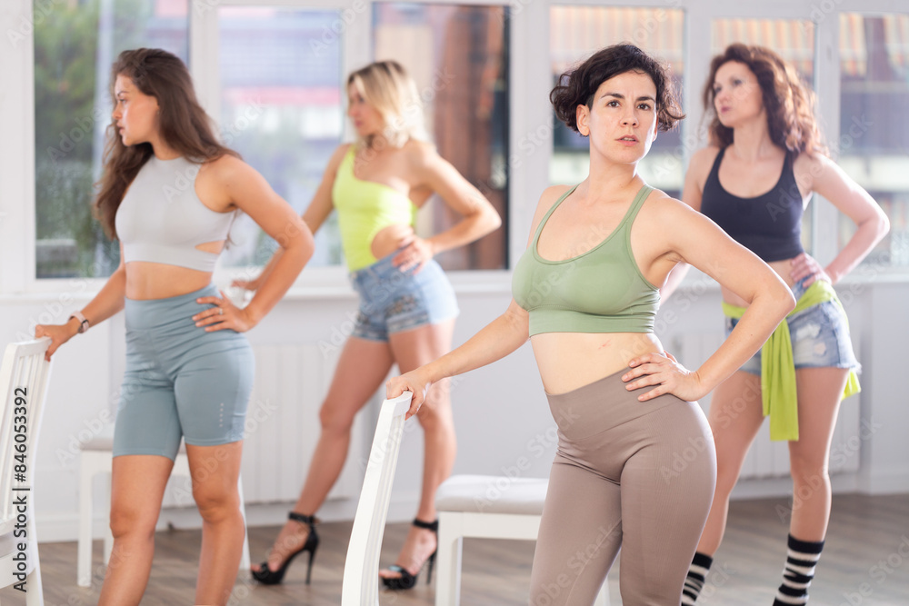 Fototapeta premium Group of girls unleash their energy and dance passionately near a chair in high heels in a dance studio. His powerful moves combined with the elegance of high heels