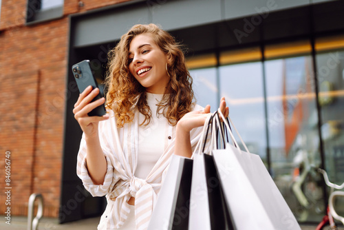 Cuadro en lienzo Young Woman use of mobile phone and hold with shopping bag