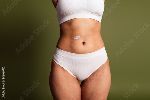 No filter cropped photo of lady stomach underwear lingerie loving body positive apply skin balm isolated khaki color background © deagreez