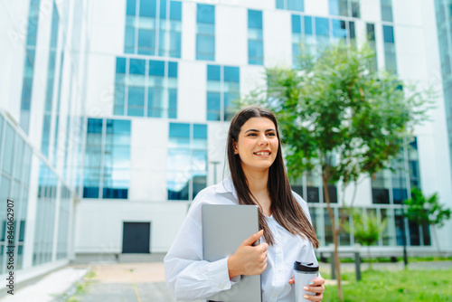 One young successful business woman going to work at business office modern building while holding coffee and laptop 