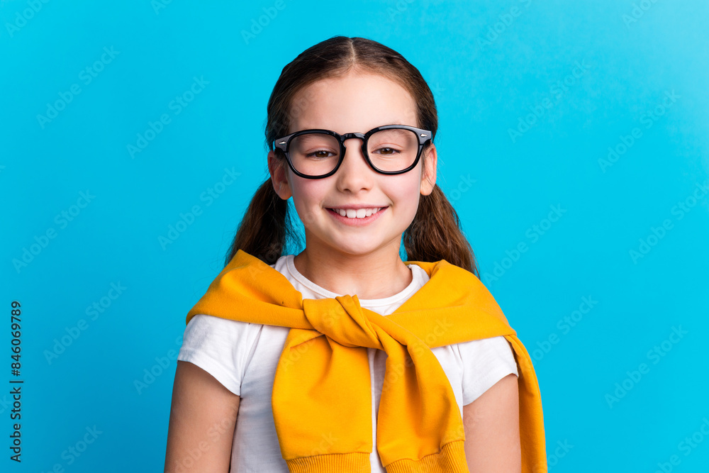 Photo of sweet lovely small girl wear tied pullover spectacles smiling empty space isolated blue color background Photo of sweet lovely small girl wear tied pullover spectacles smiling empty space isolated blue color background