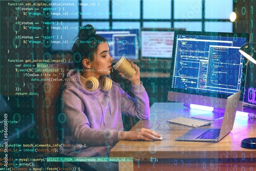 Young female programmer drinking coffee while working in office photo