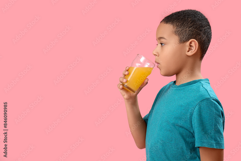 Little African-American boy with glass of orange juice on pink background Little African-American boy with glass of orange juice on pink background