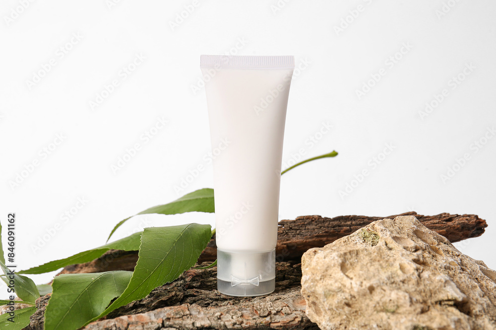 Composition with tube of cosmetic product, tree bark and plant leaf on light background Composition with tube of cosmetic product, tree bark and plant leaf on light background